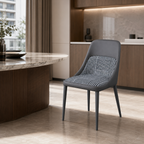 A modern gray dining chair with a woven black-and-white patterned backrest and seat, positioned in a contemporary kitchen setting next to a marble-topped island.