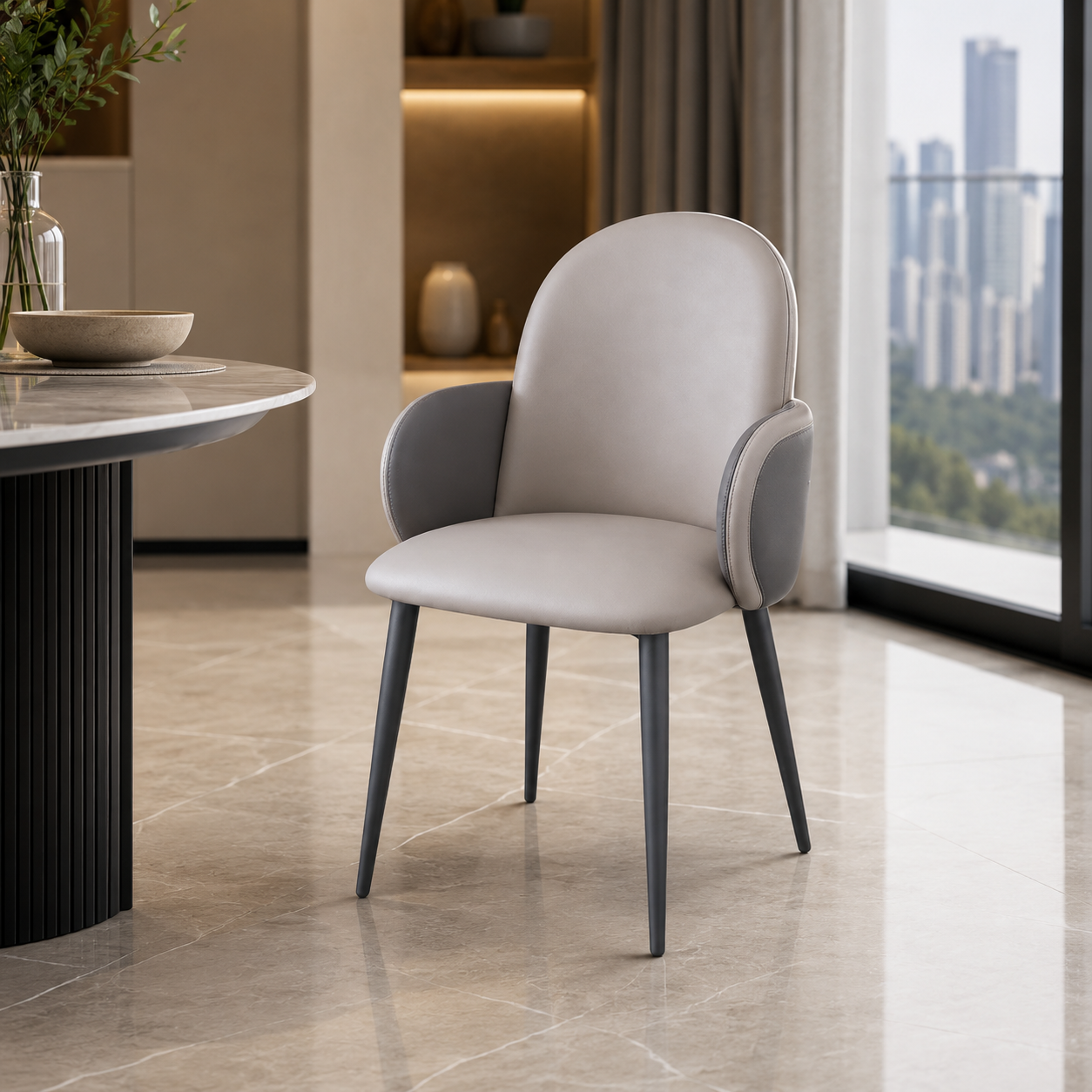 A modern upholstered dining chair with a light beige seat and back, dark gray armrests and legs, shown in a contemporary interior setting with a marble table and large windows.