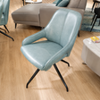 Light blue chair with black legs on a wooden floor in a living room setting.