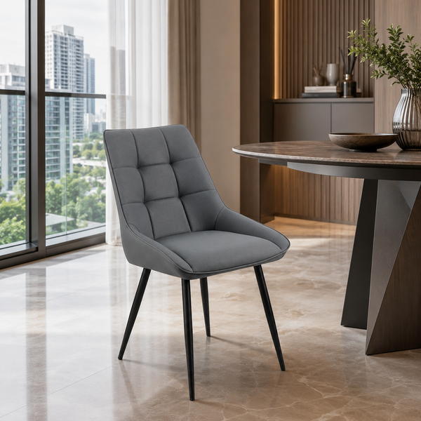 A modern gray upholstered dining chair with a tufted backrest and black tapered legs, shown in a stylish contemporary dining room next to a wooden table.