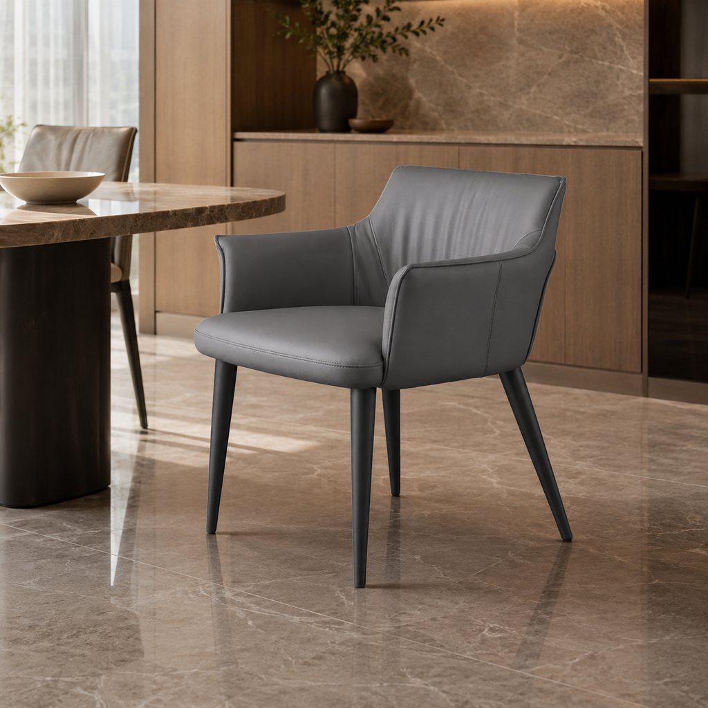 A modern gray upholstered dining chair with tapered black legs, shown in a contemporary dining room setting with a marble-topped table and warm wood cabinetry in the background.