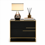 A modern black two-drawer nightstand with gold trim and gold drawer pulls, styled with a table lamp, a reed diffuser, and books on top, set against a plain white background.