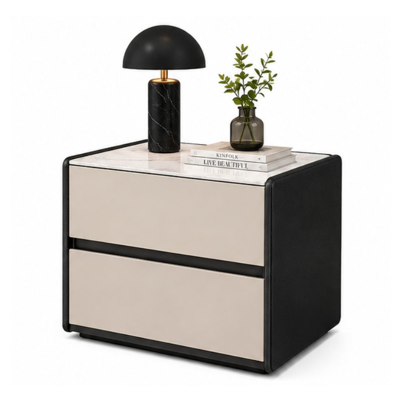 A modern two-drawer nightstand with a black frame and cream-colored drawer fronts, topped with a white marble-patterned surface. It is styled with a black marble lamp, a small plant in a glass vase, and two books on a clean white background.