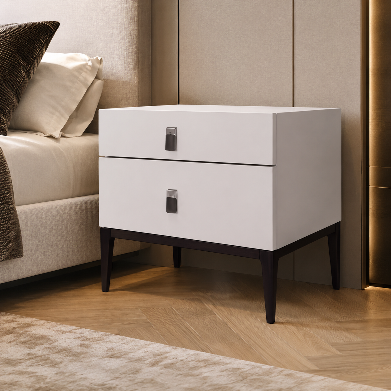 A modern two-drawer nightstand with a white finish and dark legs, styled in a contemporary bedroom next to a bed.