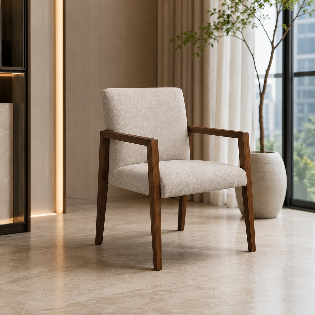A modern upholstered accent chair with a light beige fabric seat and backrest and dark brown wooden arms and legs, shown in a styled interior setting with a potted plant and curtains.