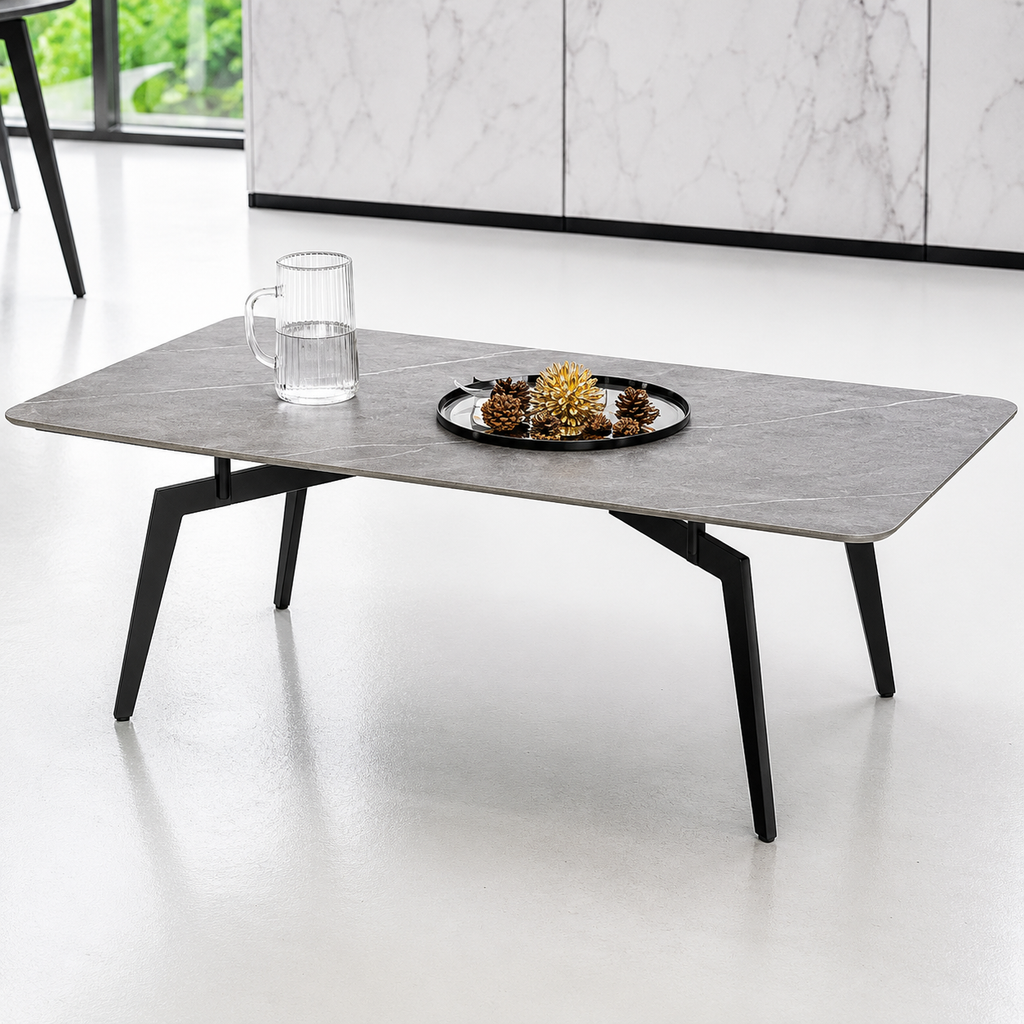 Modern coffee table with a marble-like top and black legs in a minimalistic room.
