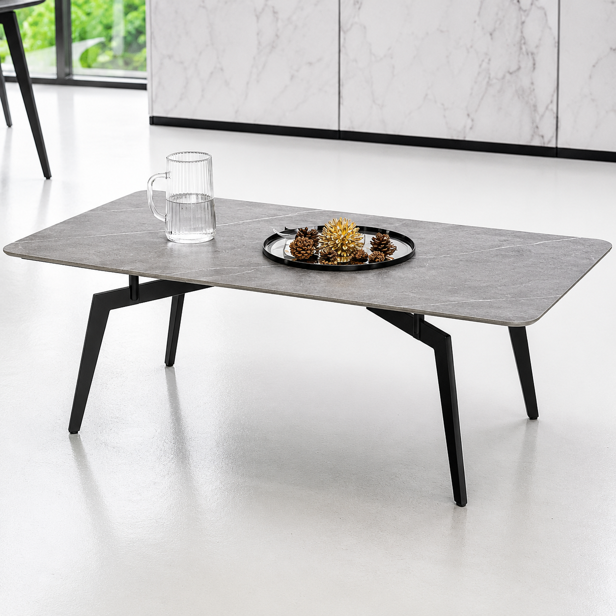 Modern coffee table with a marble-like top and black legs in a minimalistic room.