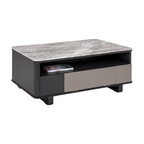 A modern rectangular coffee table with a gray marble-patterned top, a black body, and a lower shelf featuring a dark panel on the left and a light taupe panel on the right. A remote control rests inside the open shelf.