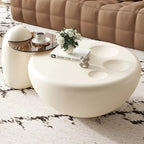 Round white coffee table with a glass top in a living room setting.