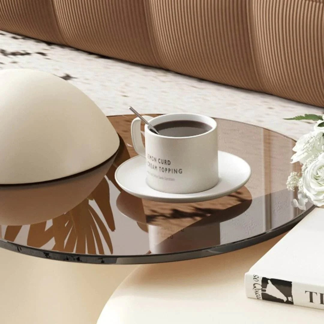 Coffee cup with saucer on a glass coffee table in a living room setting.
